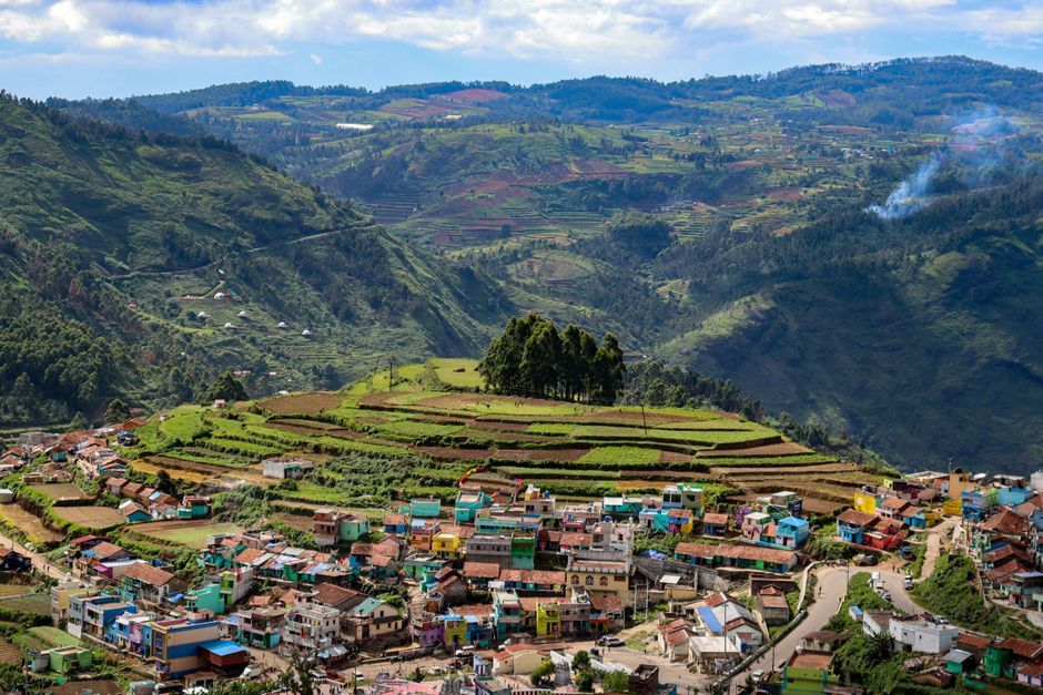 A breathtaking aerial shot of Kodaikanal's lush countryside and colorful village, depictin