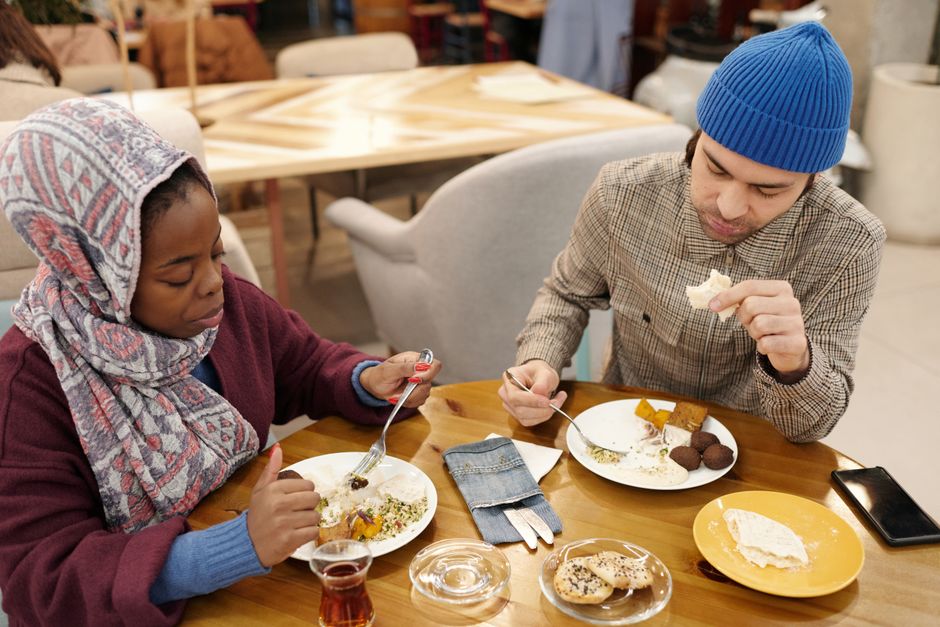 A multiethnic couple dining indoors, enjoying a Middle Eastern meal.
