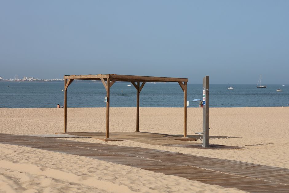 Serene sandy beach with a wooden pergola and the ocean in El Puerto de Santa María, Spain.