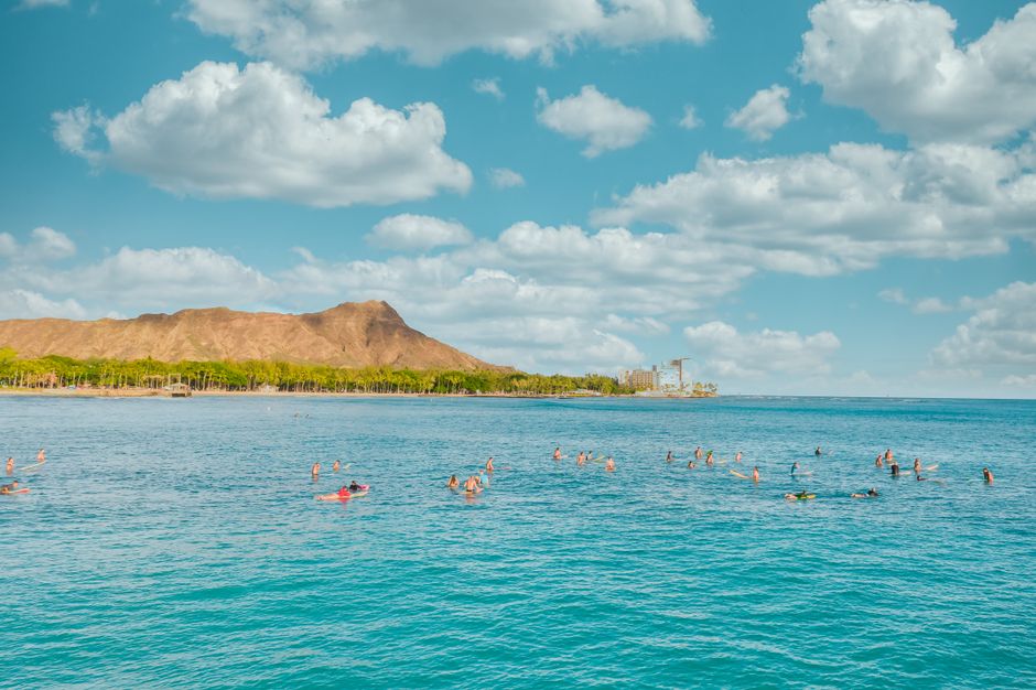 Surfers enjoying the waves near Diamond Head in a tropical paradise setting.