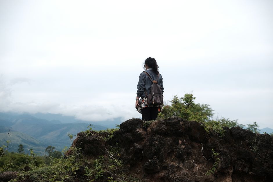 A female traveler enjoys a foggy morning overlooking the lush green hills of Jantho, Indonesia.
