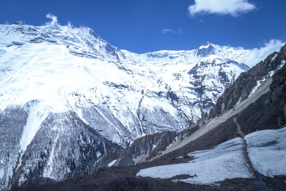 Majestic snow-capped mountains under a clear blue sky in Manang, Nepal, capturing winter's serene beauty.