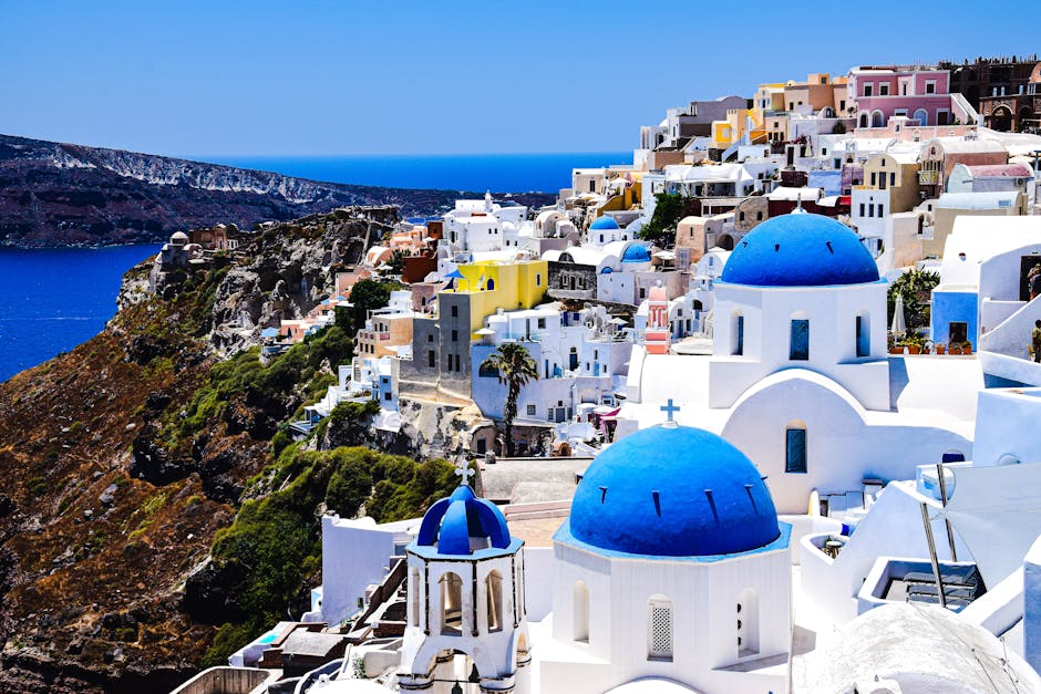 Aerial view of Santorini's famous blue-domed churches and whitewashed buildings overlooking the Aegean Sea.