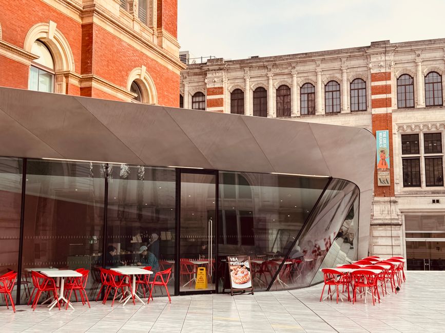 Contemporary cafe with red chairs set against a historic architectural backdrop, offering 
