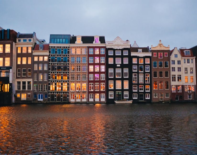 Beautiful view of iconic Amsterdam canal houses reflecting on the water at dusk.