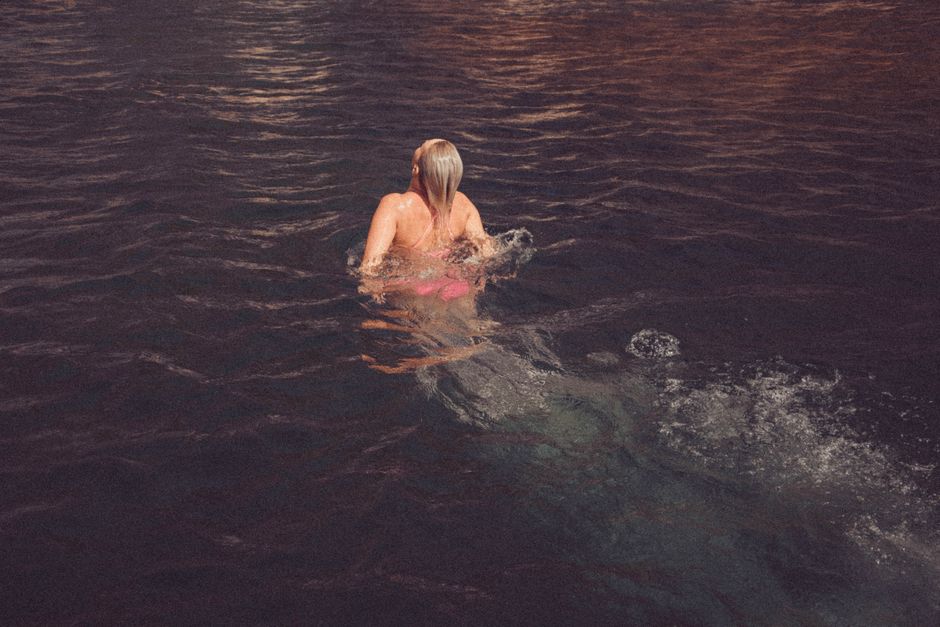 Woman swimming in natural body of water during daytime, peaceful scene