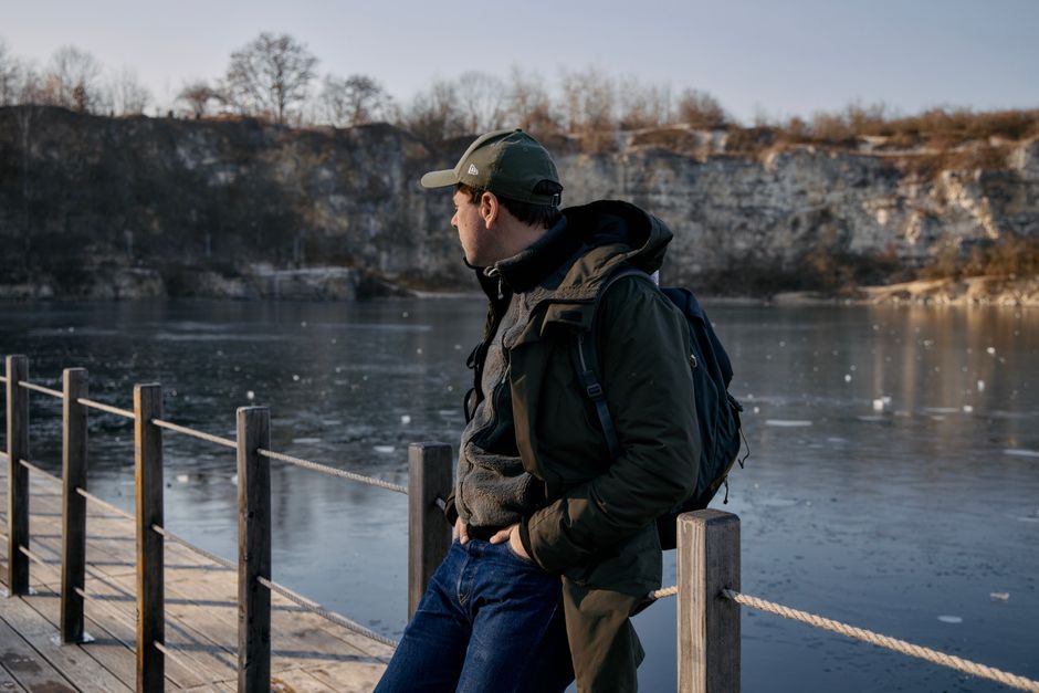 Man admiring the serene winter scenery at Kraków's frozen quarry lake.