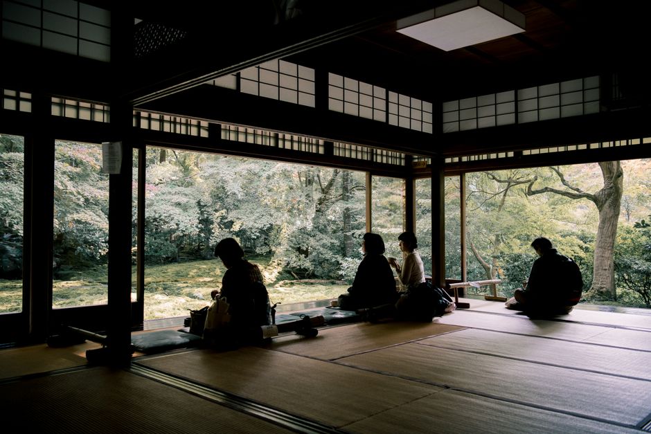 Silhouetted figures enjoy a serene view from a traditional Kyoto room.