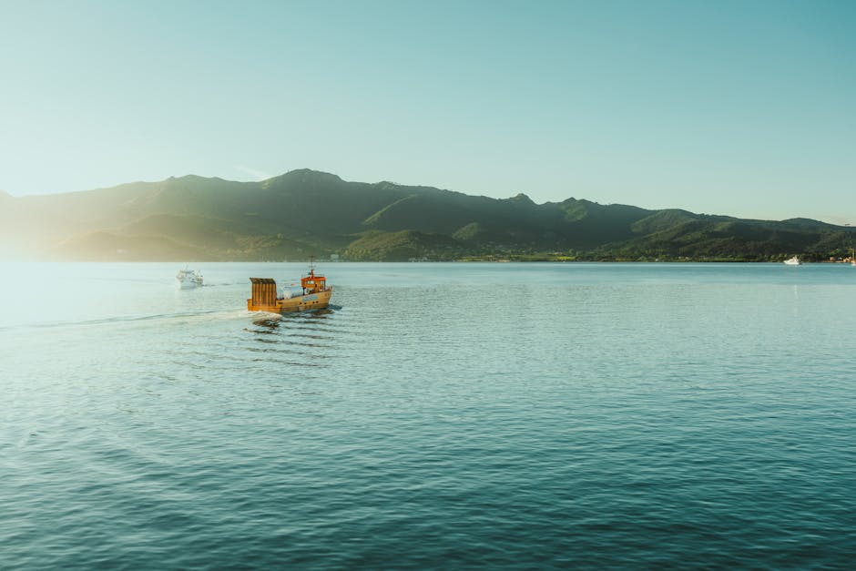 Tranquil scene of boats sailing on a peaceful lake with mountains in the background under clear skies.