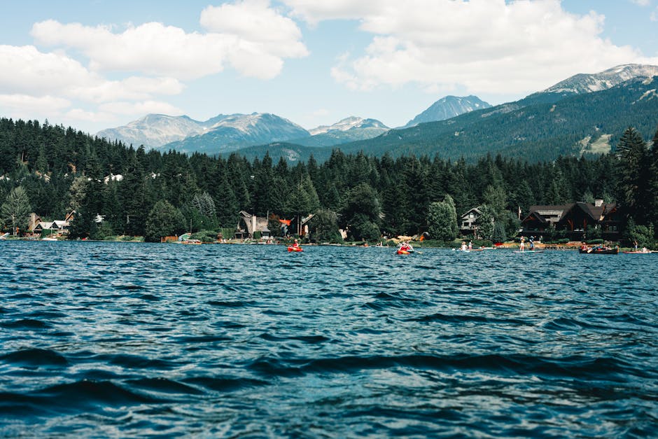 Picturesque lakeside view in Whistler, BC featuring mountains, trees, and outdoor recreation.