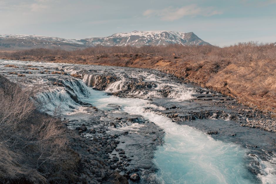 Breathtaking view of an Icelandic waterfall with mountains in spring, showcasing natural beauty.