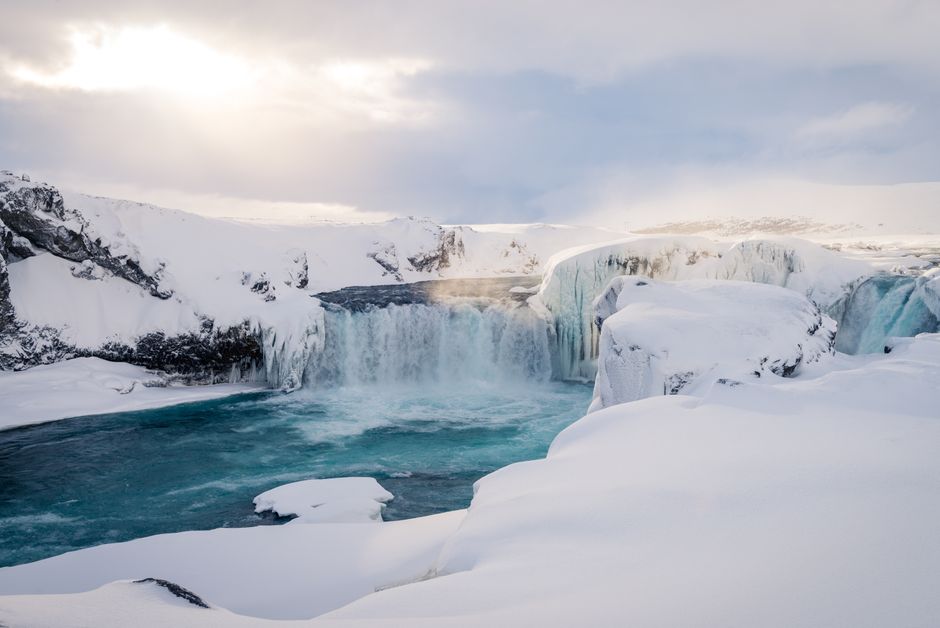 Breathtaking view of a snowy waterfall surrounded by icy landscapes during winter. Serene and beautiful.