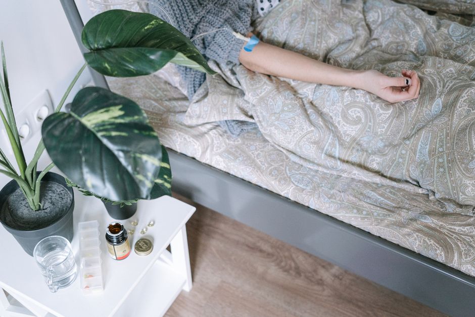 Close-up of a patient resting, surrounded by medicinal items and a bedside plant.