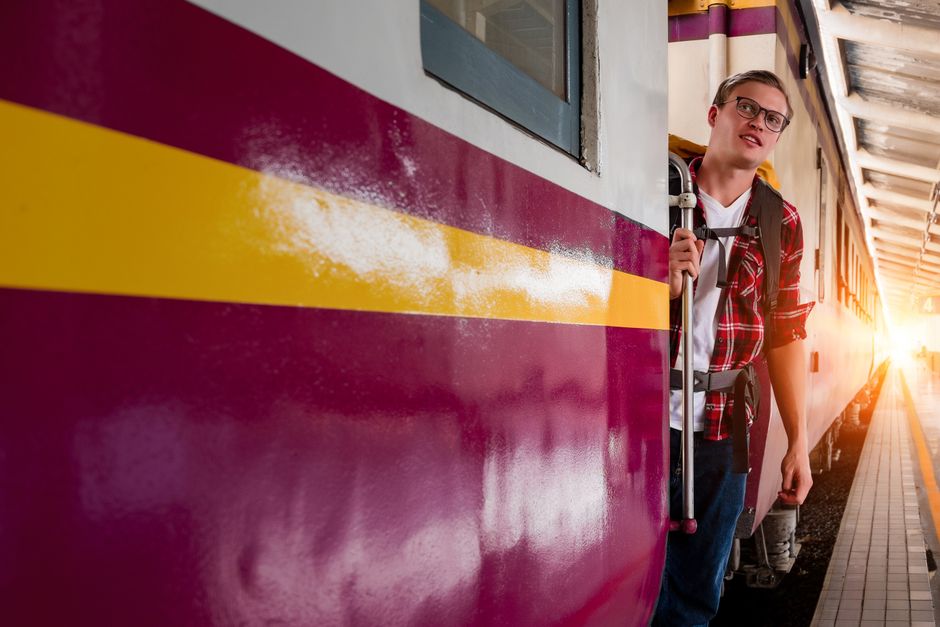 A young man with a backpack prepares to board a train at an urban station, capturing the spirit of travel and exploration.