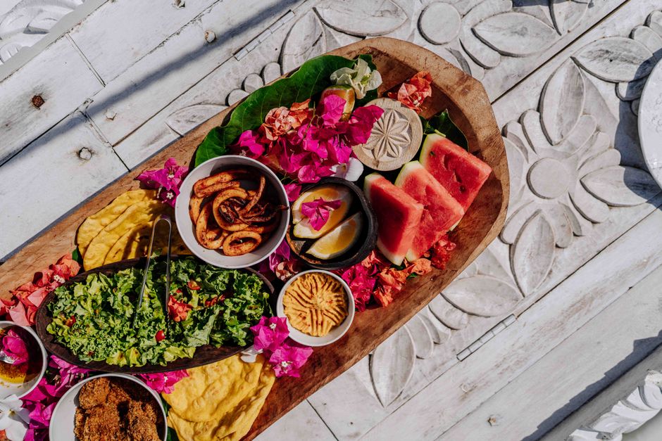 Colorful platter of Zanzibar cuisine with fresh fruits, seafood, and vibrant flowers.