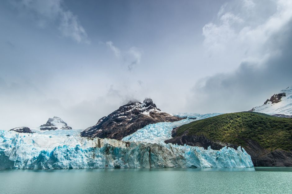 Breathtaking view of a frozen glacier with snowy mountains and serene lake.