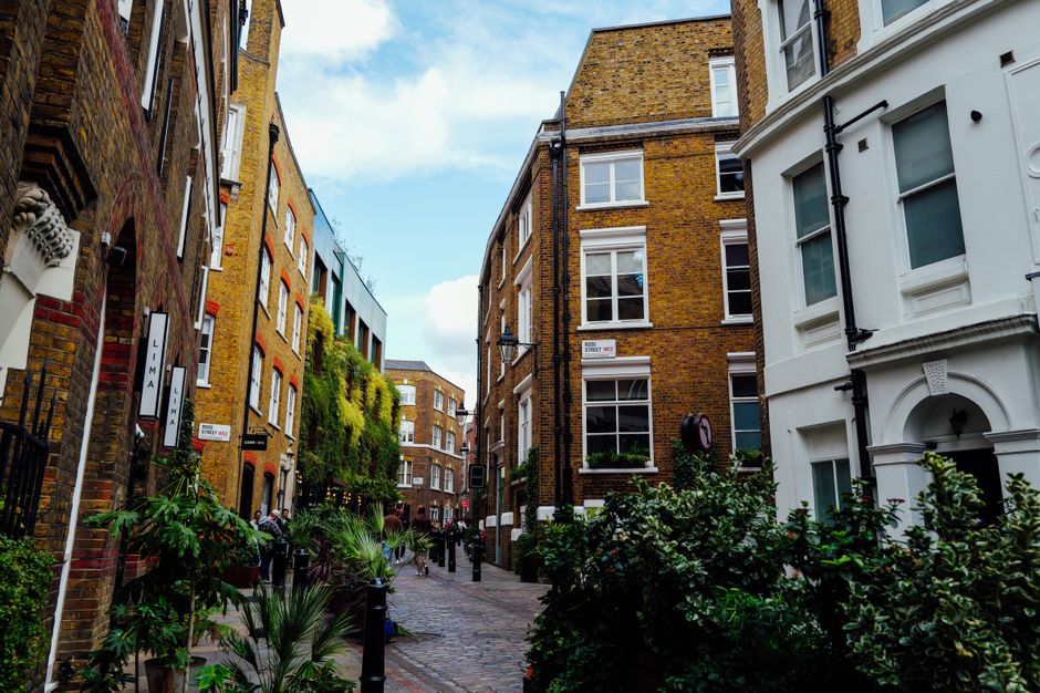 Picturesque alleyway in a cityscape with historic brick buildings and lush greenery.
