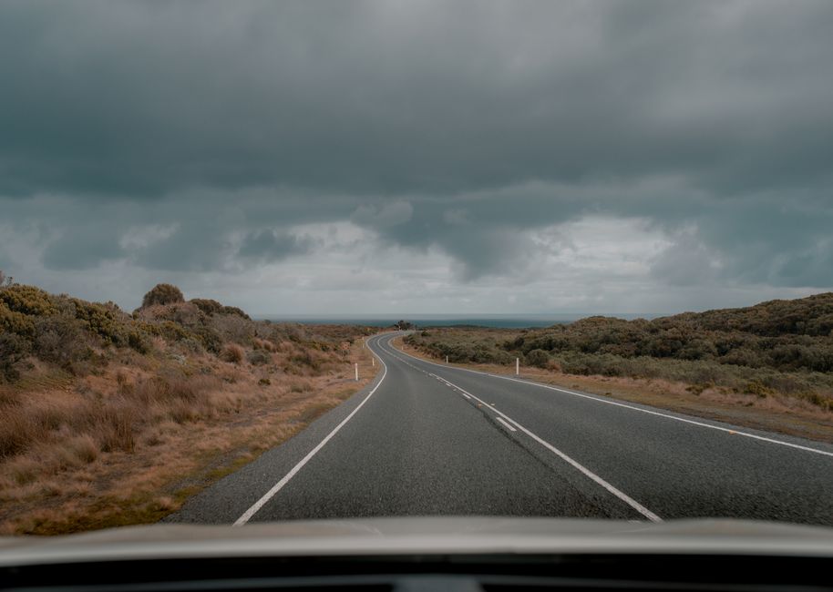 Empty road under dramatic clouds in Anglesea, Australia. Perfect for travel and nature themes.