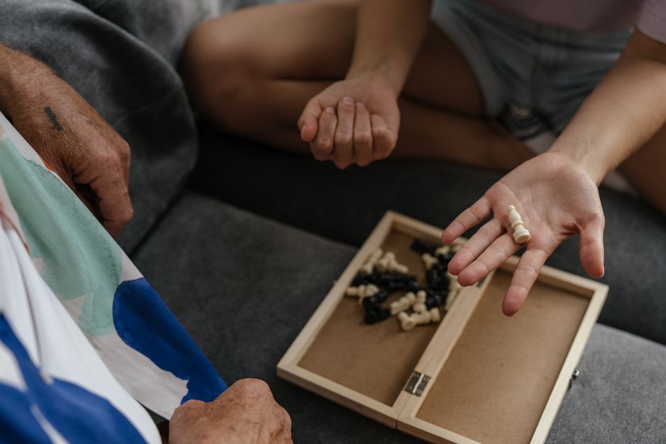 Hands holding and examining chess pieces from a wooden box during a casual game.