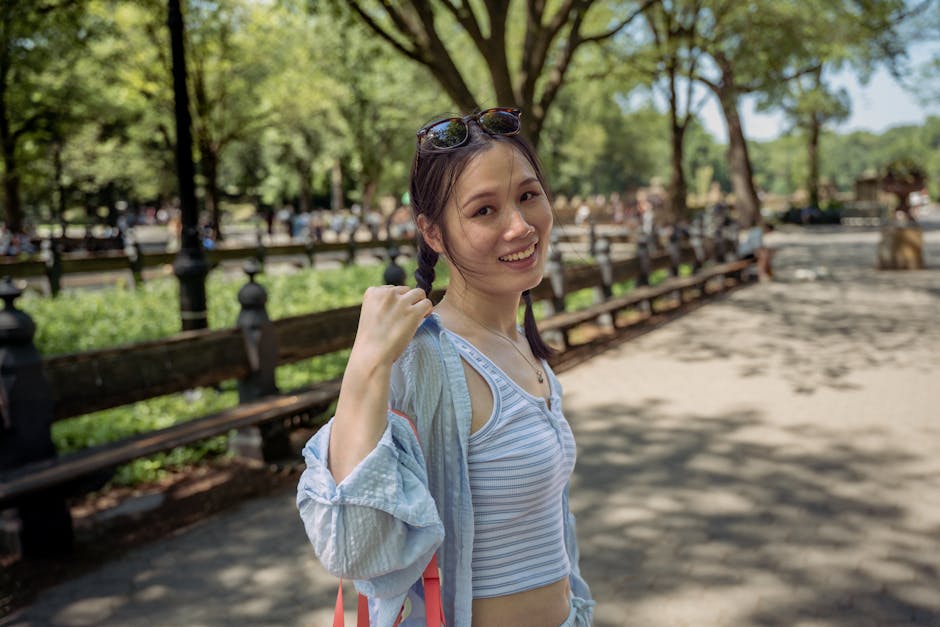 Young woman enjoying a sunny day in Central Park, New York City, surrounded by lush greenery.